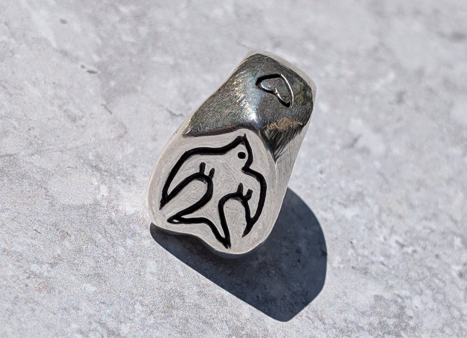 Silver handmade ring with hand carved swallow bird motif on the front and heart motif on the side