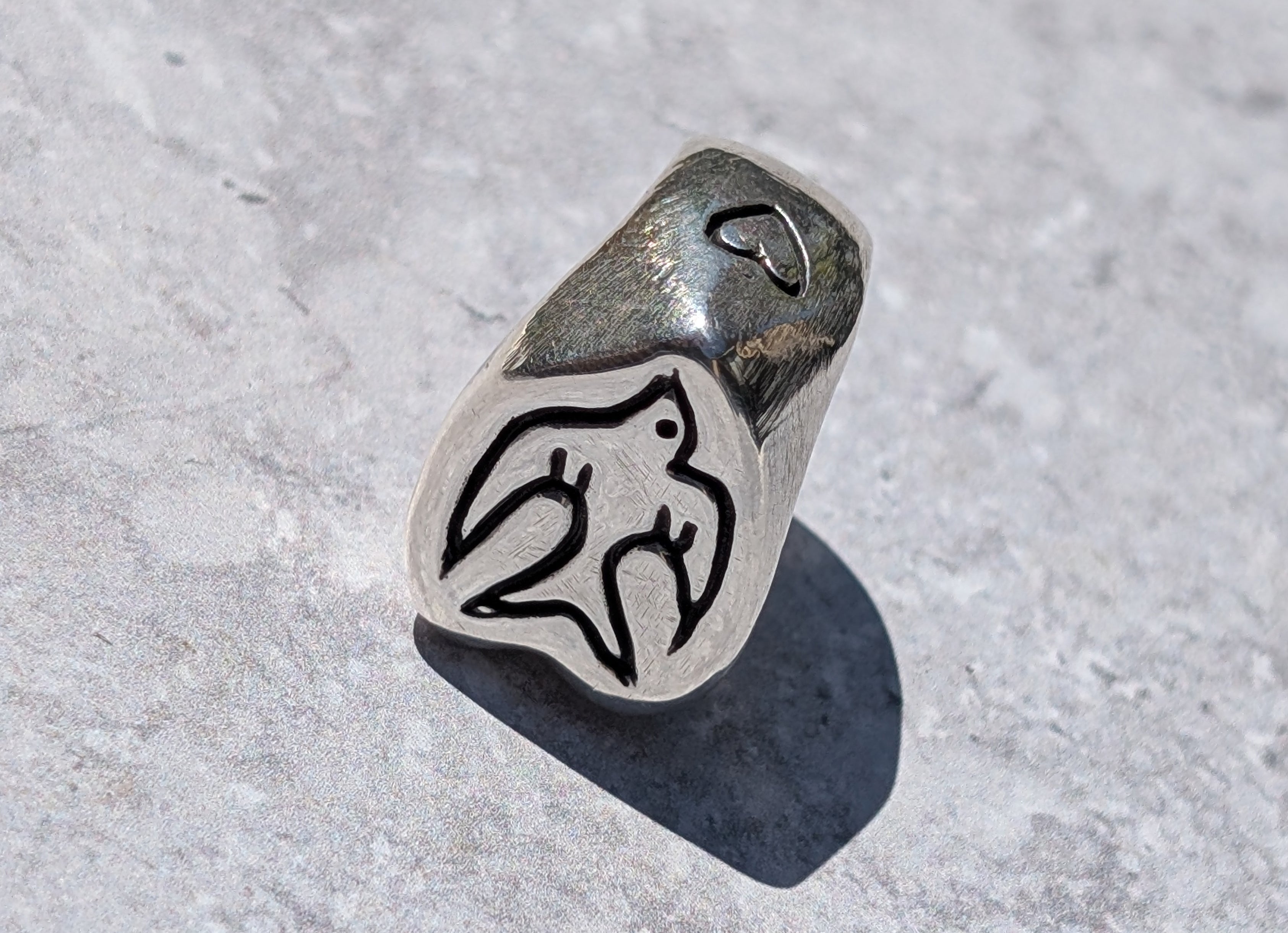 Silver handmade ring with hand carved swallow bird motif on the front and heart motif on the side 